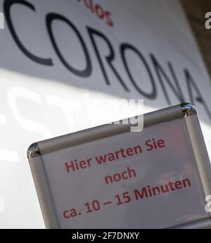 Monaco, Germania. 06 Aprile 2021. Un cartello con la scritta 'attendere qui per circa 10-15 minuti' si trova di fronte ad una stazione di prova gratuita Corona ospitata nel Deutsches Museum. Credit: Peter Kneffel/dpa/Alamy Live News Foto Stock