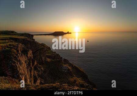 Testa di verme Rhossili Bay al tramonto e una barca singola, penisola di Gower, Galles del Sud, Regno Unito Foto Stock