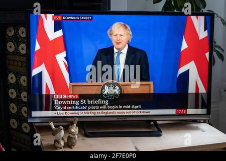 Briefing con Boris Johnson affiancato da Union Jacks nella nuova sala stampa di Downing Street. Testo ''certificato Covid' piloti da iniziare a metà aprile' Foto Stock