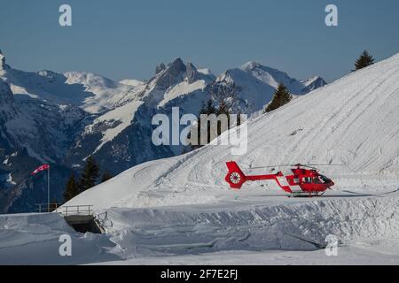 Elicottero di soccorso parcheggiato su un elipad provvisorio in montagna pronto per l'azione. Elicottero di soccorso rosso all'aperto. Foto Stock