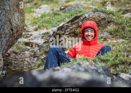 Ritratto di sorridente alpinista che si rilassa in un prato alpino Foto Stock