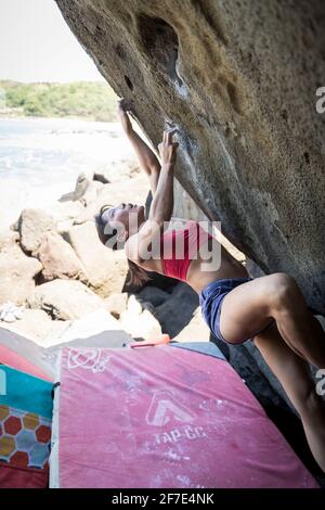 Donna agile che scalda un muro con un crash pad sotto lei per la sicurezza Foto Stock