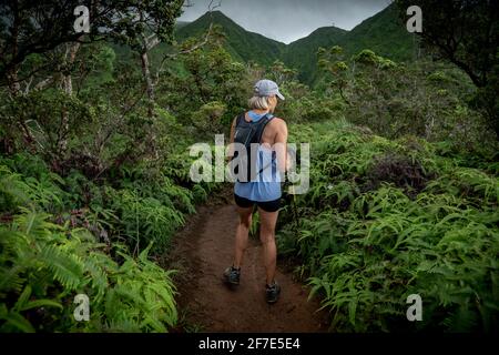 Donna bionda che indossa un nero backpacking trekking alle Hawaii Foto Stock