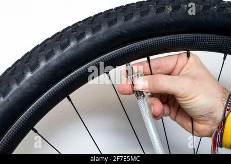 Una persona sta gonfiando una ruota di bicicletta con l'aiuto di aria compressa e di un manometro. Dettaglio di un ugello dell'aria montato sulla valvola della ruota. Foto Stock
