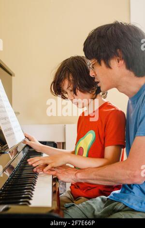 Un padre e un figlio si siedono vicini alla realizzazione del piano musica Foto Stock