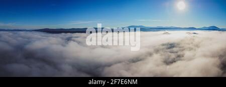 Il drone di mattina presto panorama del campo di Planinsko Polje in Slovenia durante la fitta nebbia sulla pianura, con solo colline più alte come Slivnica sono visti st Foto Stock