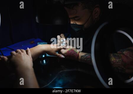 Uomo manicurista che applica la resina ai chiodi di un cliente, primo piano Foto Stock