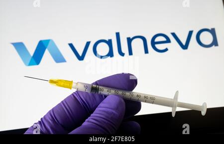 Concetto di vaccino Valneva COVID-19. Il logo della siringa e della società Valneva sullo schermo di sfondo sfocato. Stafford, Regno Unito, 6 aprile 2021. Foto Stock