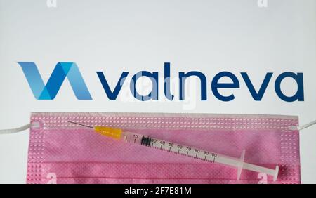 Concetto di vaccino Valneva COVID-19. Siringa, maschera facciale e logo aziendale Valneva sullo schermo sfocato. Stafford, Regno Unito, 6 aprile 202 Foto Stock