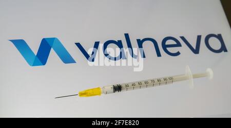 Concetto di vaccino Valneva COVID-19. Il logo della siringa e della società Valneva sullo schermo di sfondo sfocato. Stafford, Regno Unito, 6 aprile 2021. Foto Stock