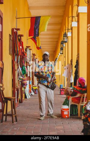 CARTAGENA, COLOMBIA, FEBBRAIO 20 2017: Uomo latino con camicia delle hawaii in piedi nel corridoio arcuato del mercato di Las Bovedas, tenendo una tazza di plastica Foto Stock