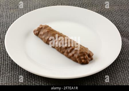 Caramelle al cioccolato con riso soffiato e caramello al centro piastra bianca sulla tela grigia Foto Stock