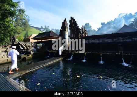 Sacerdote indù balinese che prega presso la piscina purificante del tempio Tirta Empowerl di Bali, Indonesia. Foto Stock