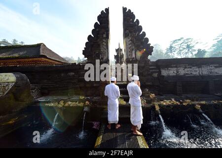 Sacerdote indù balinese che prega presso la piscina purificante del tempio Tirta Empowerl di Bali, Indonesia. Foto Stock