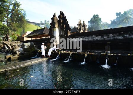 Sacerdote indù balinese che prega presso la piscina purificante del tempio Tirta Empowerl di Bali, Indonesia. Foto Stock