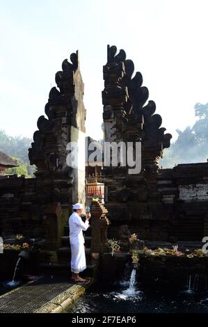Sacerdote indù balinese che prega presso la piscina purificante del tempio Tirta Empowerl di Bali, Indonesia. Foto Stock