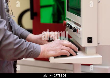 L'operatore programma la macchina per il taglio e l'incisione laser. Messa a fuoco selettiva. Foto Stock