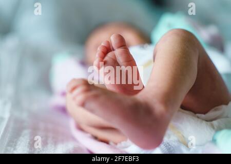 Primo piano sui piedi del neonato sconosciuto che giace sopra letto a casa con spazio per la copia Foto Stock