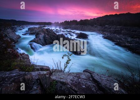 Un'alba rosa e viola incredibilmente vibrante sul fiume Potomac al Great Falls Park durante una tarda mattinata di ottobre. Foto Stock