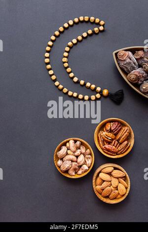 Ramadan Kareem e iftar cibo musulmano, concetto moderno di vacanza. Ciotole di legno con noci e frutta secca e la luna fatta di perle Foto Stock