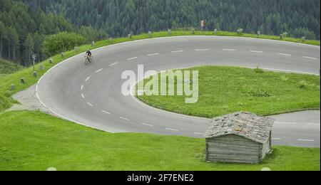 Ciclista singola in salita su una strada curvilinea con serpentine o tornanti mentre si sale a Grossglockner, alto passo montano in Austria Foto Stock