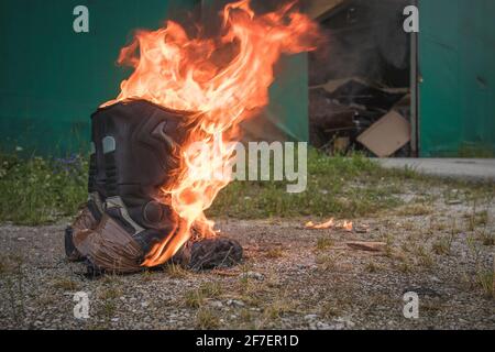 Stivali da motocicletta neri e indossati che bruciano e sono in fiamme. Scarpe da motocicletta sul fuoco. Concetto di scarpe da rogo. Foto Stock