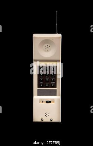 Un vecchio telefono cordless bianco d'epoca degli anni '80 isolato in nero. Tastiera marrone visibile e antenna argento. Vista frontale. Foto Stock