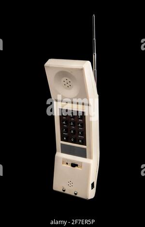 Un vecchio telefono cordless bianco d'epoca degli anni '80 isolato in nero. Tastiera marrone visibile e antenna argento. Vista frontale. Foto Stock