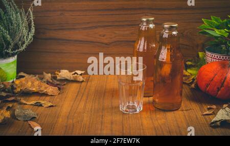 Succo di mela naturale fresco fatto in casa in bottiglie di vetro su un tavolo di legno con alcuni ornamenti. Ambiente autunnale per prodotti naturali autunnali. Foto Stock