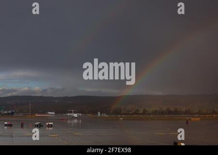 Rainbow sta sorgendo sul grembiule dell'aeroporto internazionale di Zurigo con uno dei jet planes che si avvicina alle porte. Foto Stock