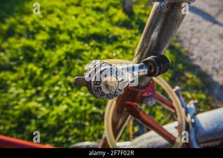 Dettaglio del lucchetto a combinazione di numeri economici indossati su una vecchia bicicletta, con prato verde appena dietro la serratura. Parco o fuori in periferia di una città Foto Stock