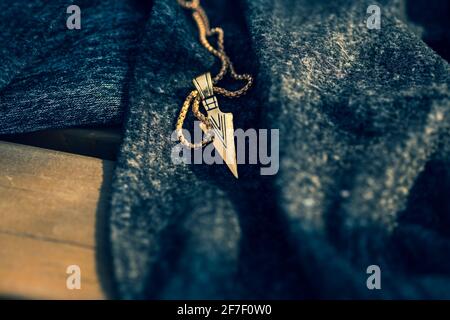 Collana con freccia pendente colore dorato sparare in una giornata di sole closeup esterno. Messa a fuoco selettiva Foto Stock