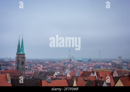 Panorama di case nella città di Nurnberg in un freddo tardo giorno d'autunno, pieno di nebbia, nebbia, nuvole basse e con foglie che cadono dagli alberi. Foto Stock