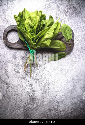 Le foglie di spinaci sorrel da giardino giacciono su una tagliere di legno. Foto Stock