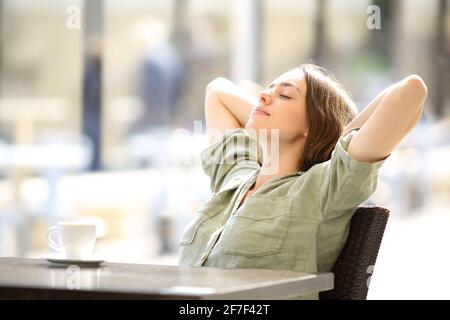 Donna rilassata che riposa con le braccia sulla testa in un caffè negozio Foto Stock