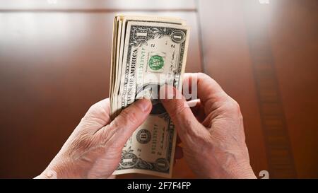 Una donna anziana conta dollari, vista ritagliata. Ultimi soldi per la vita, redditi bassi. Concetto di risparmio. Foto Stock