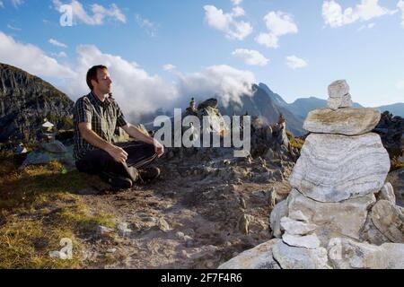 Un uomo medita tra piramidi di pietra sul Passo di Nufenen a 2478 m, Canton Vallese, Svizzera, Europa Foto Stock