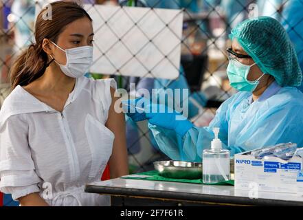 Una donna che indossa una maschera facciale riceve una dose del vaccino CoronaVac (Sinovac). Diversi ministri del governo e tutti i parlamentari del partito Bhumjaithai hanno iniziato la quarantena di 14 giorni dopo essere stati in stretto contatto con i nuovi casi di Covid-19. Foto Stock