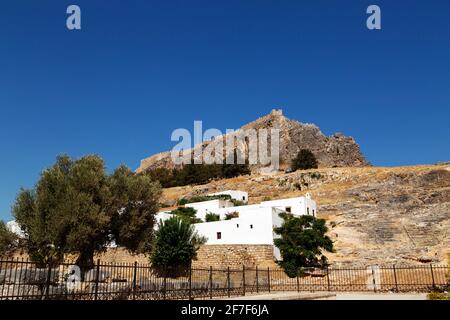 L'Acropoli di Lindian sorge su case bianche nel villaggio di pescatori di Lindos, a Rodi, in Grecia. Il sito collinare ha un antico tempio greco dedicato Foto Stock