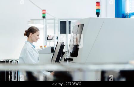 Donna operatrice in fabbrica che utilizza una saldatrice per l'elettronica produzione Foto Stock