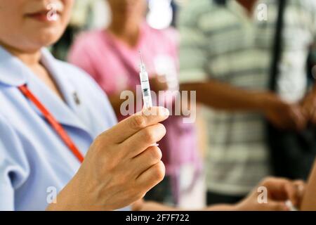 Il medico o l'infermiere indossano guanti bianchi medici utilizzando una siringa per ago per prelevare un campione di sangue dal braccio del paziente in ospedale. Foto Stock