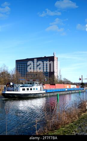 Wolfsburg, Germania, 21 febbraio 2021: Nave da carico con container sul canale di fronte all'edificio amministrativo della fabbrica di automobili Volkswagen in Foto Stock