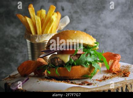 Hamburger con rucola e salsa maionese servito su tavola di legno Foto Stock