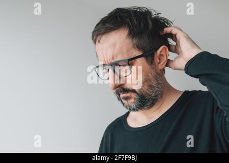 Dimenticanza - uomo medio-adulto dimenticato con occhiali al chiuso, cercando di ricordare Foto Stock