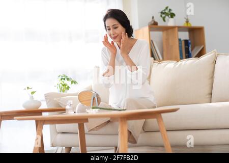 Donna matura che applica aloe vera a casa Foto Stock