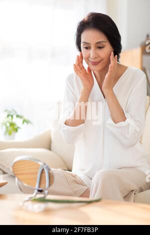 Donna matura che applica aloe vera a casa Foto Stock