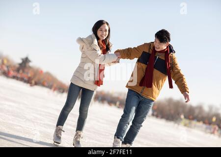 Felice giovane coppia pattinaggio su ghiaccio all'aperto Foto Stock