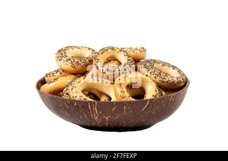 Ssushka Baranka ricoperta di semi di papavero. Spuntino con biscotti salati dell'Europa orientale in conchiglia di cocco marrone naturale, vista laterale, isolato su bianco. Foto Stock