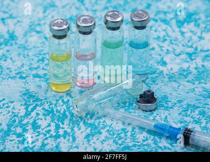 Prevenzione delle malattie stagionali. Fiale mediche, siringhe e una maschera su sfondo verde. Vaccinazione contro covid-19. Foto Stock