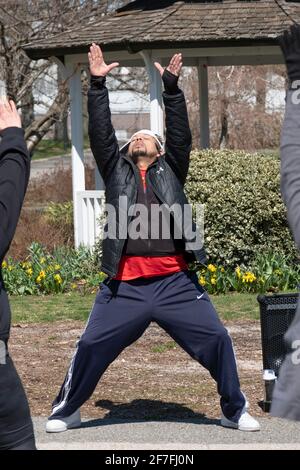 Un uomo conduce una lezione di Zumba attraverso un vigoroso allenamento di danza in un parco a Queens, New York City. Foto Stock